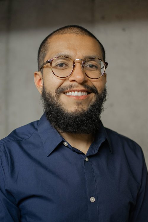 Headshot photo of a man with a beard and glasses